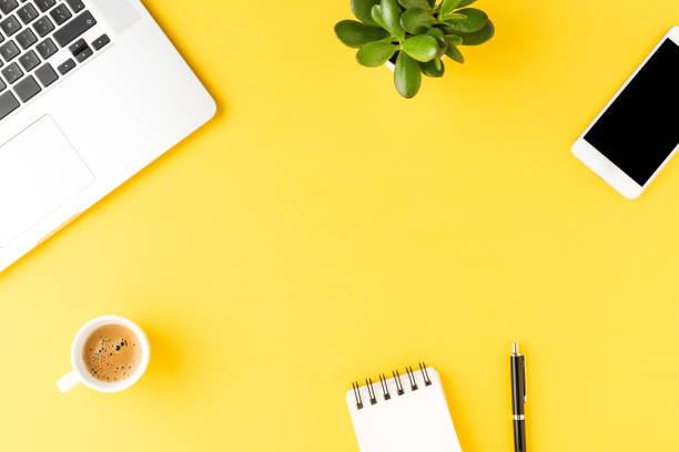 istock Office desktop with laptop and accessories on yellow background. Top view 1255401335