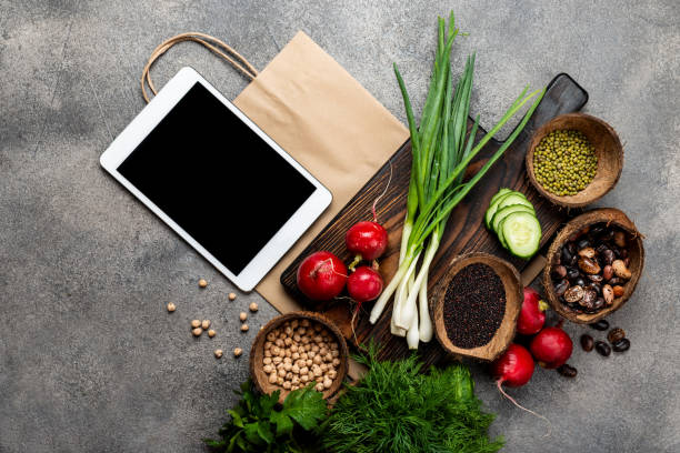 istock tablet computer and shopping paper bag with vegetables cereals greens top view. 1255401542