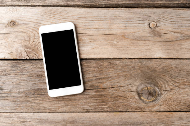istock Smart phone with empty screen on wooden desk. Top view 1255401683