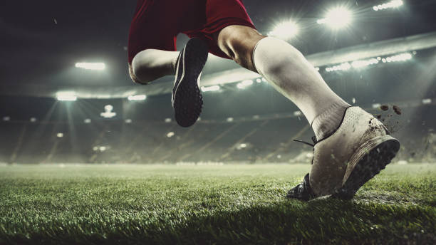 Close up football or soccer player at stadium in flashlights - motion, action, activity concept Leader. Close up football player at stadium in flashlight. Young sportsman during the match. Moment of attacking, catching. Concept of sport, competition, winning, action, motion, overcoming. match sport stock pictures, royalty-free photos & images