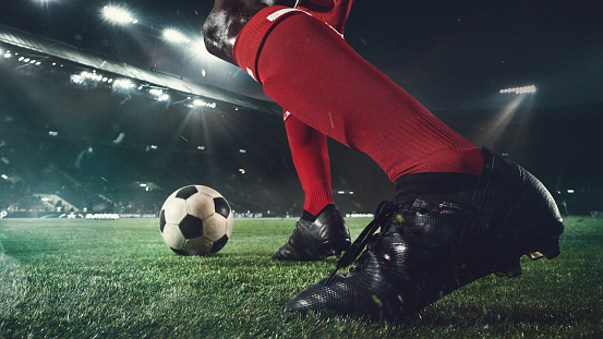 Emotions. Close up football player at stadium in flashlight. Young sportsman during the match. Moment of attacking, catching. Concept of sport, competition, winning, action, motion, overcoming.