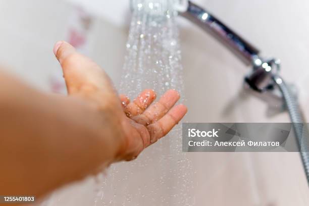 Hands Check The Temperature Of The Shower Water A Mans Hand Under A Stream Of Water Selective Focus Stock Photo - Download Image Now