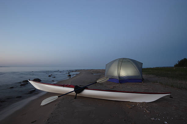 Kayak and Illuminated Tent On Beach at Night stock photo