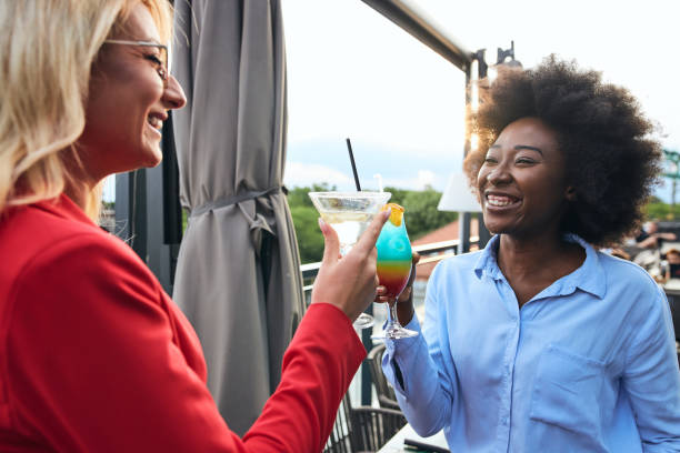 istock Cheerful female colleagues enjoying cocktail drinks on a social gathering 1255405651
