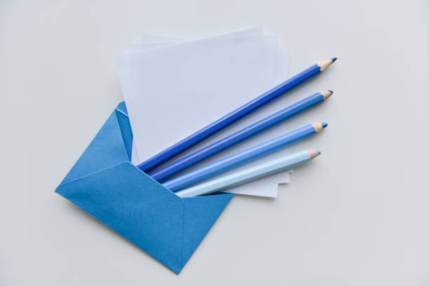 selective focus, four blue pencils and white papers out of the blue envelope