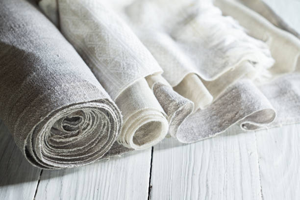 Old homespun and modern factory linen fabrics in rolls Old homespun and modern factory linen fabrics in rolls on a white wooden table flax weaving stock pictures, royalty-free photos & images