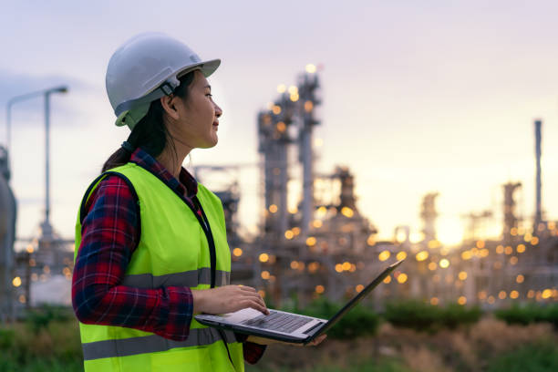 ingénieur pétrochimique femme asiatique travaillant la nuit avec ordinateur portable à l’intérieur de l’usine de l’usine de raffinerie de pétrole et de gaz usine de nuit pour le contrôle de la qualité de sécurité inspecteur. - energy management photos et images de collection