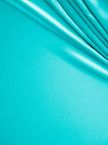 istock Beautiful elegant wavy turquoise silk or satin luxury cloth fabric texture, abstract background design. 1255410410