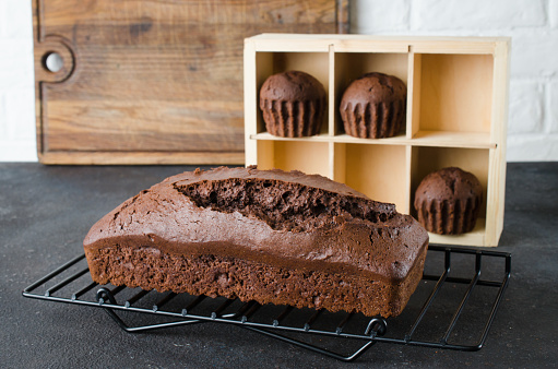 Freshly baked homemade chocolate bread or cake and chocolate muffins on dark background, rustic style. Selective focus.
