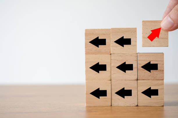 istock Hand putting red arrow print screen on wooden cube changing direction with black arrow. It is business disruption and different thinking idea concept. 1255412015