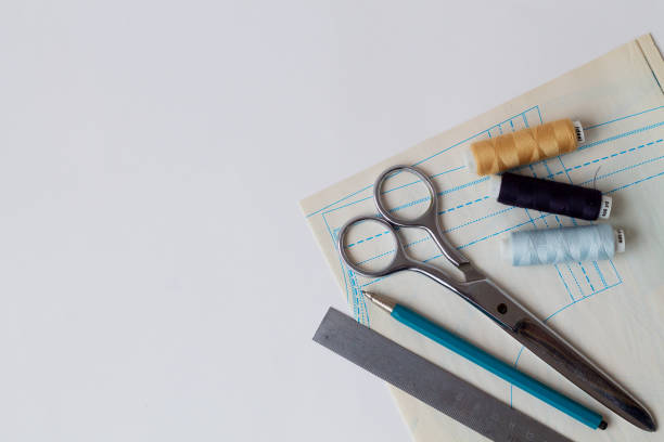 istock needlework. sewing thread, pencils, ruler, scissors and patterns on a white table of a fashion designer. top view. copy space. offices tools on white background 1255412950