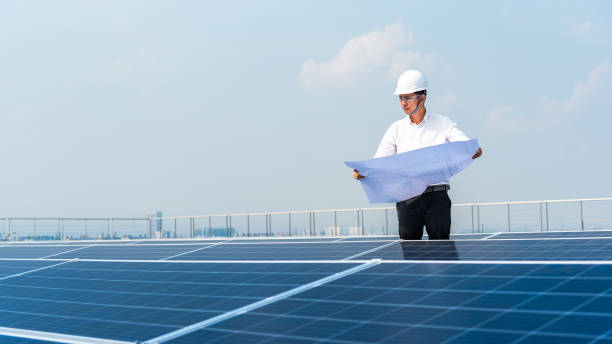 istock Electrical engineer is carrying a blueprint to install the solar cell on a high building deck. 1255416444