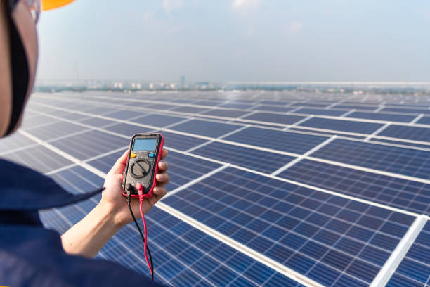 Electrical engineers are carrying electrical measuring instruments at the solar cell farm installed on the roof of the building.