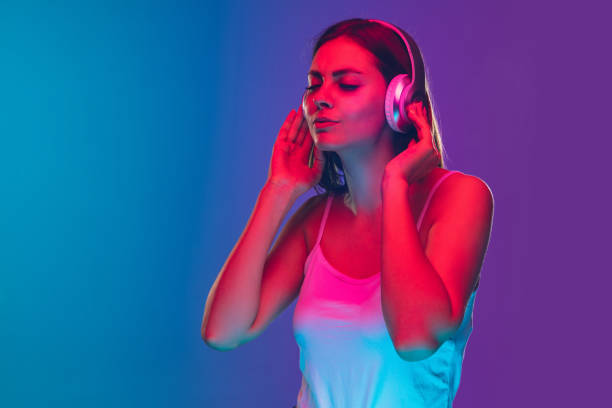 istock Caucasian young woman's portrait isolated on gradient purple-blue background in neon light 1255417120