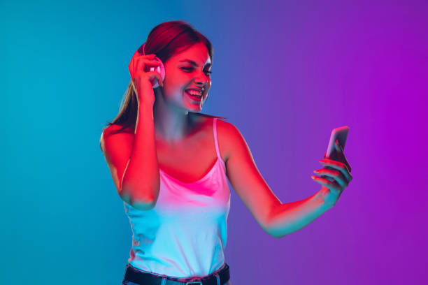 istock Caucasian young woman's portrait isolated on gradient purple-blue background in neon light 1255417122