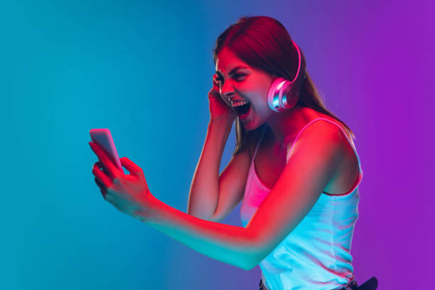 istock Caucasian young woman's portrait isolated on gradient purple-blue background in neon light 1255417130