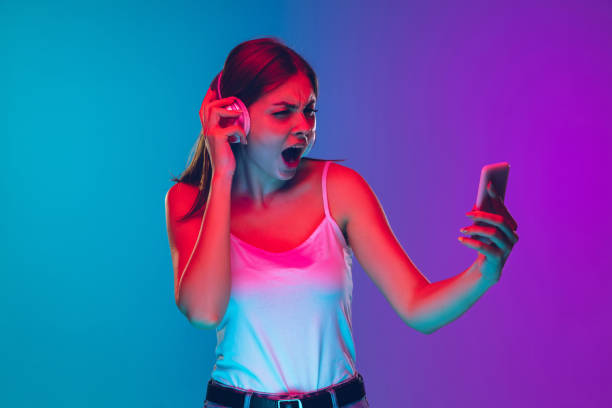 istock Caucasian young woman's portrait isolated on gradient purple-blue background in neon light 1255417131