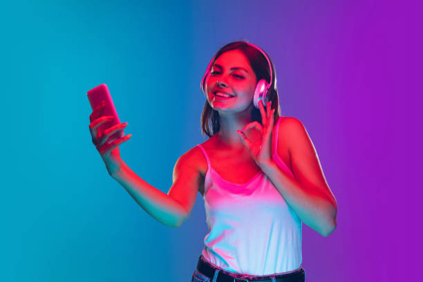 istock Caucasian young woman's portrait isolated on gradient purple-blue background in neon light 1255417132