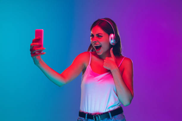istock Caucasian young woman's portrait isolated on gradient purple-blue background in neon light 1255417134
