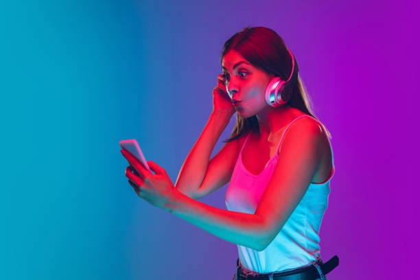 istock Caucasian young woman's portrait isolated on gradient purple-blue background in neon light 1255417135