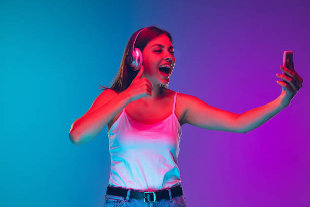 istock Caucasian young woman's portrait isolated on gradient purple-blue background in neon light 1255417136