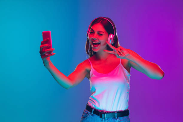 istock Caucasian young woman's portrait isolated on gradient purple-blue background in neon light 1255417137
