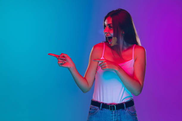 istock Caucasian young woman's portrait isolated on gradient purple-blue background in neon light, cinema, movie watching 1255417155