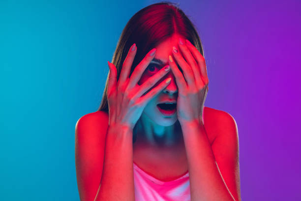 istock Caucasian young woman's portrait isolated on gradient purple-blue background in neon light, cinema, movie watching 1255417157