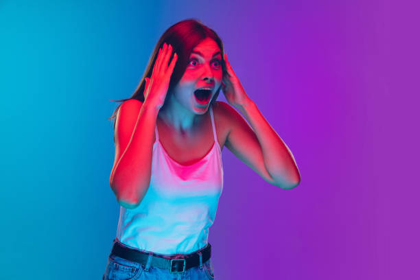 istock Caucasian young woman's portrait isolated on gradient purple-blue background in neon light, cinema, movie watching 1255417165