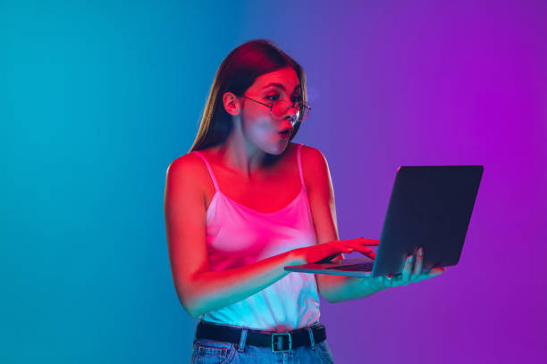 istock Caucasian young woman's portrait isolated on gradient purple-blue background in neon light, cinema, movie watching 1255417167