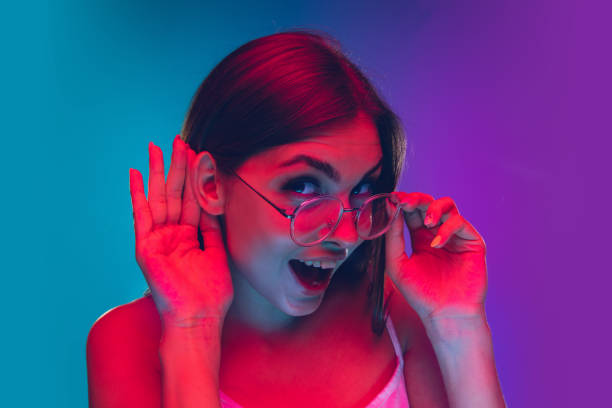 istock Caucasian young woman's portrait isolated on gradient purple-blue background in neon light, cinema, movie watching 1255417169