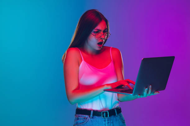 istock Caucasian young woman's portrait isolated on gradient purple-blue background in neon light, cinema, movie watching 1255417172