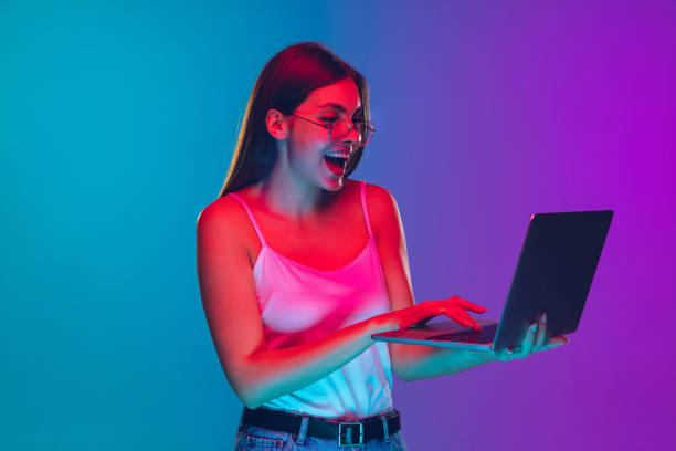 istock Caucasian young woman's portrait isolated on gradient purple-blue background in neon light, cinema, movie watching 1255417175