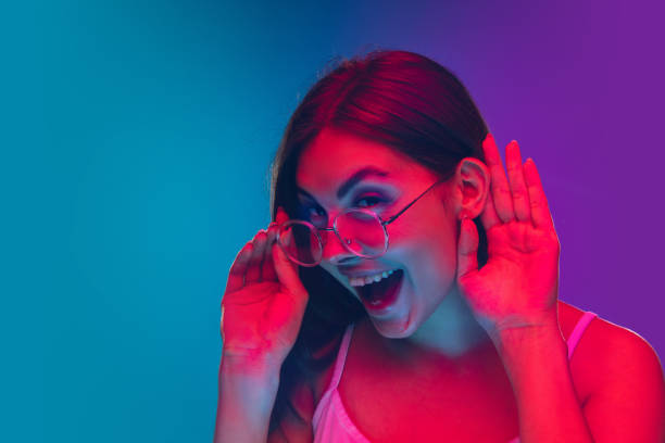 istock Caucasian young woman's portrait isolated on gradient purple-blue background in neon light, cinema, movie watching 1255417182