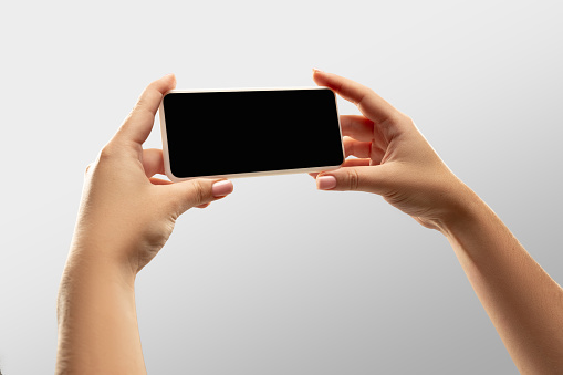 Close up female hands holding smartphone with blank screen during online watching of popular sport matches, championships. Copyspace for ad. Devices, gadgets, technologies concept.