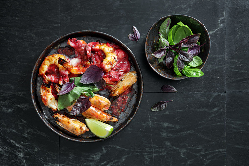 Grilled tiger prawns with celery root puree with balsamic beetroot sauce. Flat lay top-down composition on black background. Horizontal image with copy space.