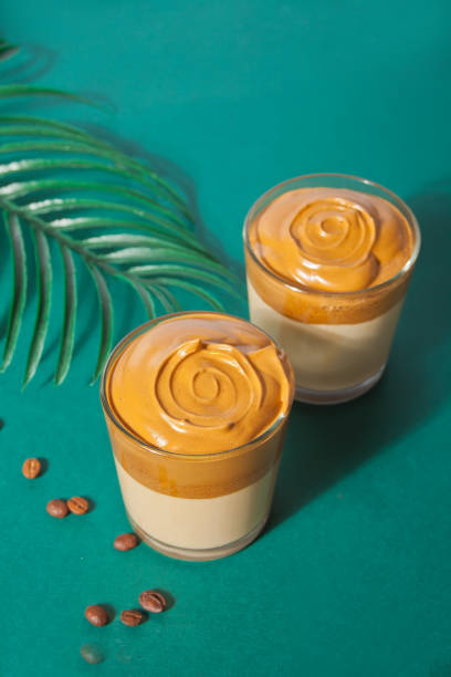 Dalgona Coffee. Fluffy creamy whipped coffee on the green background. Trendy beverage.