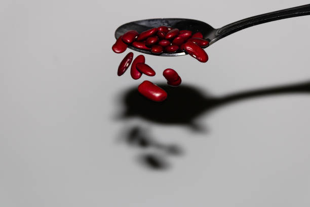 falling red kidney beans off a spoon background photo - falling beans imagens e fotografias de stock