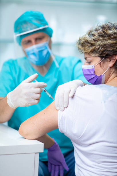 istock Female patient with face mask looking at her arm while getting flu vaccine 1255423592