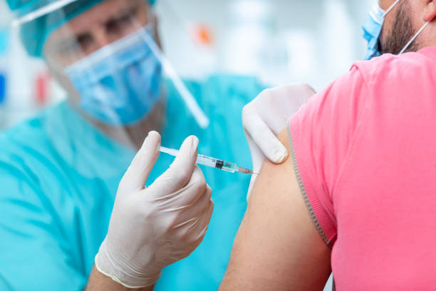istock Doctor wearing protective workwear injecting flu vaccine into patient's arm 1255423766