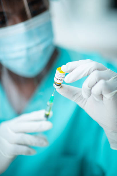 istock Doctor's hands in protective gloves pulling COVID-19 vaccine with syringe 1255423785