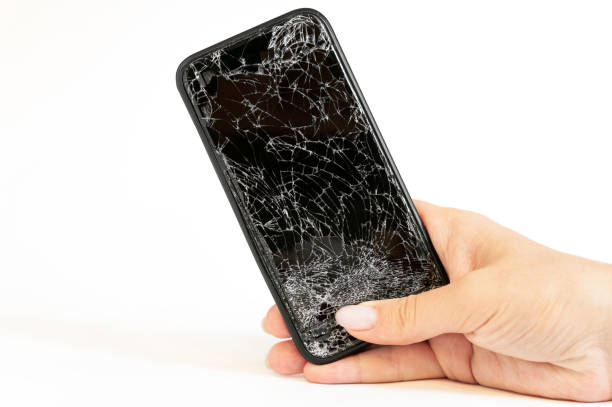 istock Modern black smartphone with highly broken screen in women hand on white background. 1255423812