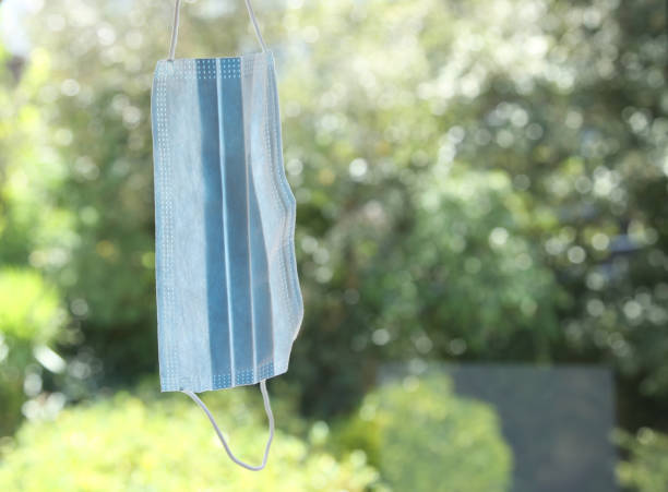 istock Coronavirus (COVID-19) outbreak concept image consisting a medical face mask hanging next to a window. 1255424651
