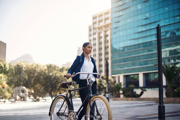 She knows the way to success Shot of a young businesswoman traveling with a bicycle through the city responsible business stock pictures, royalty-free photos & images