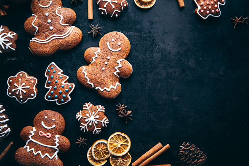 Holiday frame of Christmas gingerbread cookies, biscuits on baking paper, traditional season baked with spices, dry orange, cinnamon sticks, anis star, candy. Sweet food, new year flat lay, copyspace