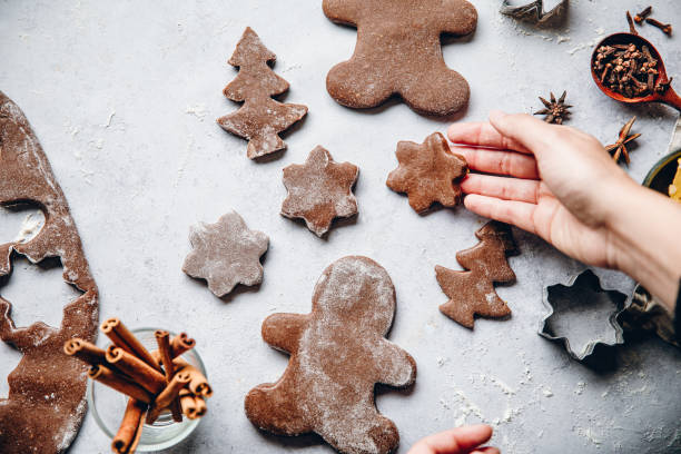 Woman preparing Christmas gingerbread cookies Woman preparing Christmas gingerbread cookies in kitchen. Female hand placing freshly made cookies with spices on table. Christmas Tree Cookie stock pictures, royalty-free photos & images