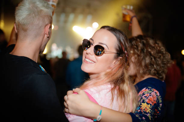 Young woman with friends on live event, looking at camera over shoulder