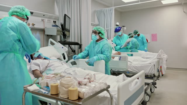 Slow motion video of frontline doctors and nurses taking care of patients in ICU during the pandemic of COVID-19.
