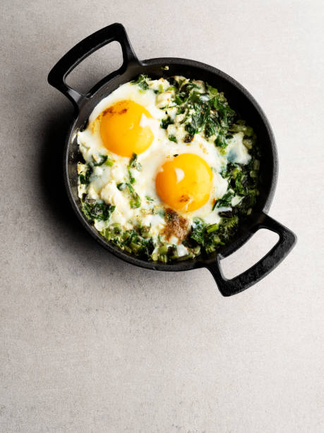 oeufs frits aux épinards, oeufs frits aux légumes, œufs shakshouka (œufs pochés dans un épinard épicé) - poêle verte photos et images de collection