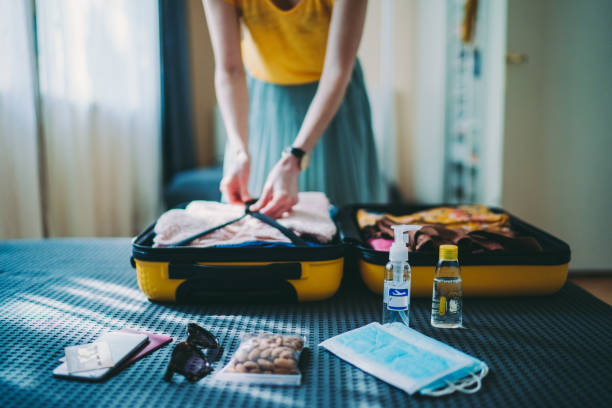 Suitcase packing for travel, COVID-19 Woman packing suitcase for summer trip, including face masks and travel-sized antibacterial hand gels belongings stock pictures, royalty-free photos & images